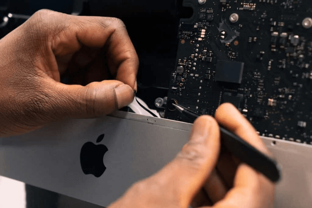 Hand using tools on a black PCB motherboard with details